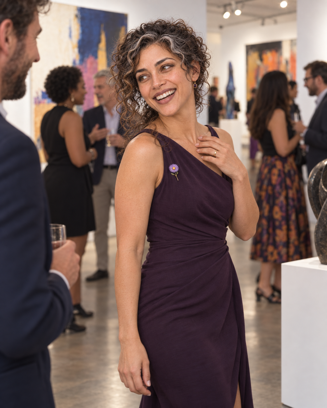 Aster Averi smiling at a museum opening beneath warm gallery lighting